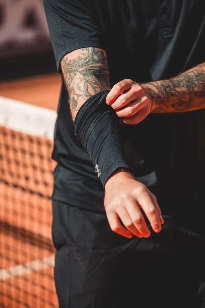 Athlete adjusting a compression sleeve over the elbow