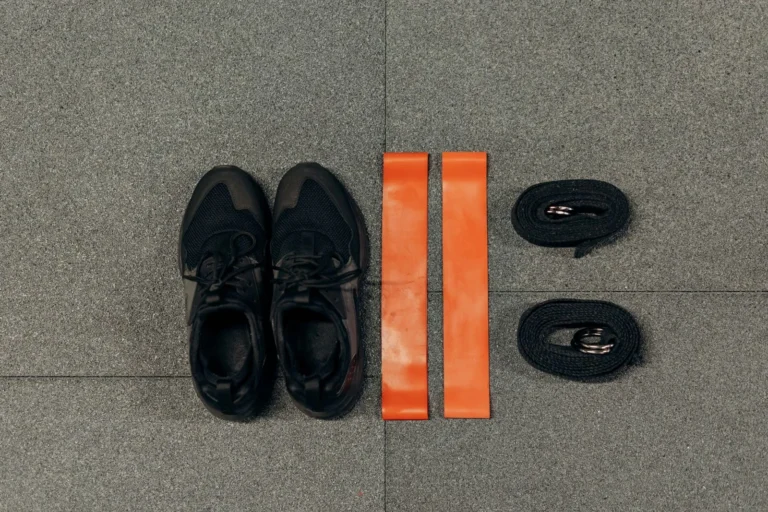 Orange fabric resistance bands beside training shoes and straps