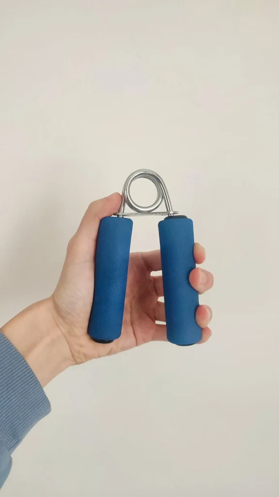 Hand squeezing a blue grip trainer