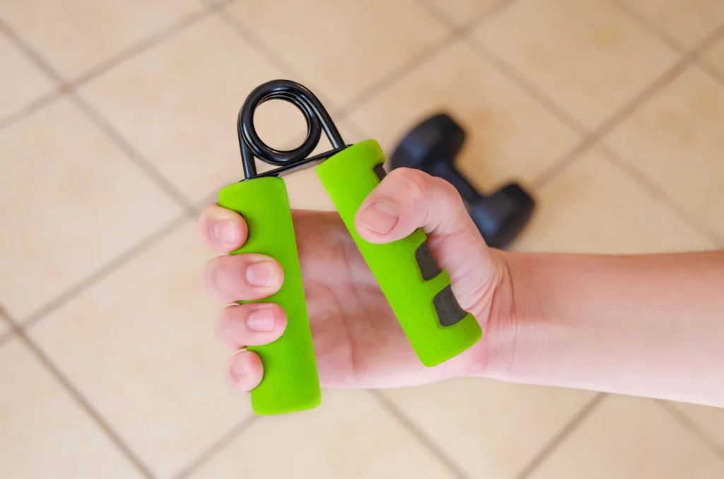Hand squeezing a green grip trainer