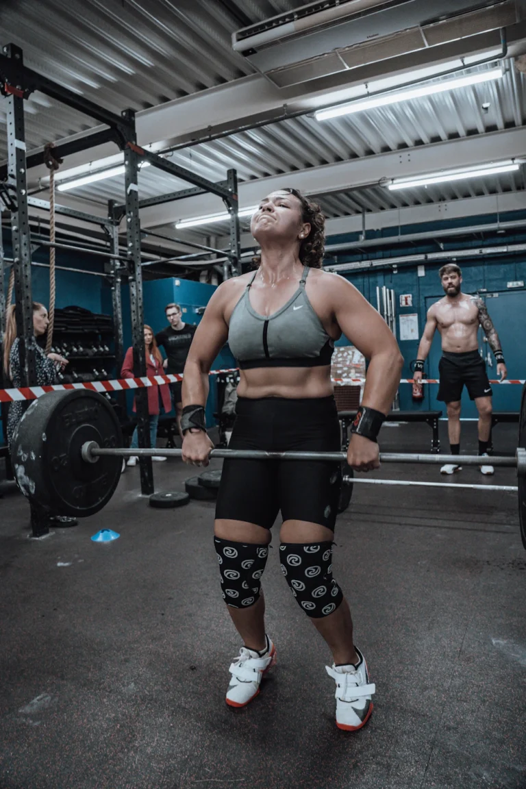 Athlete wearing black knee sleeves at a squat rack