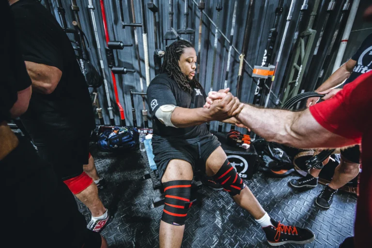 Lifter wearing red and black knee wraps in a gym