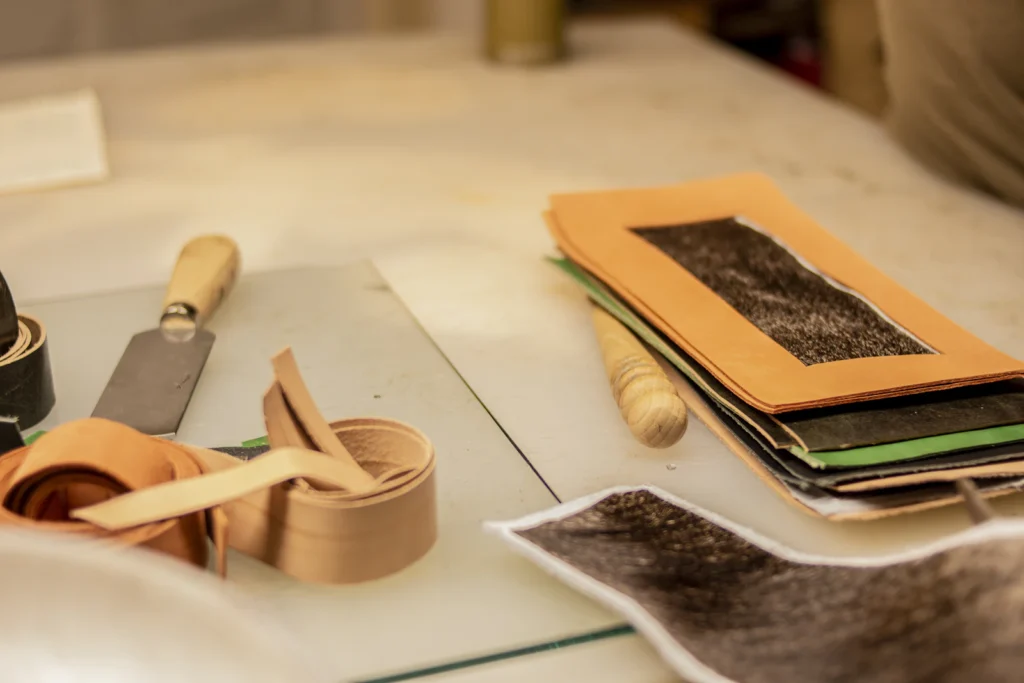 Leather pieces, patterns and hand tools on a workshop bench