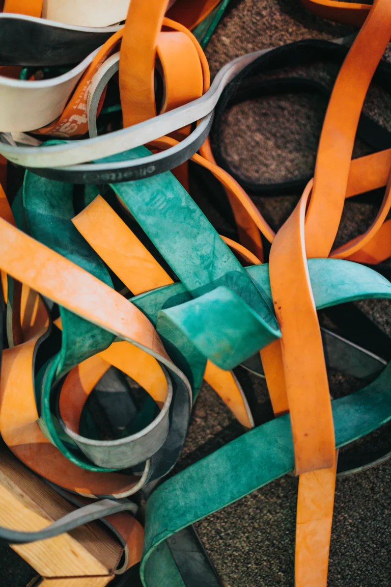 Lifting straps in orange, teal and grey webbing laid together