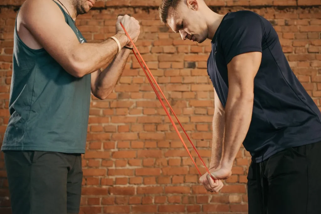 Two men training with a long latex power band