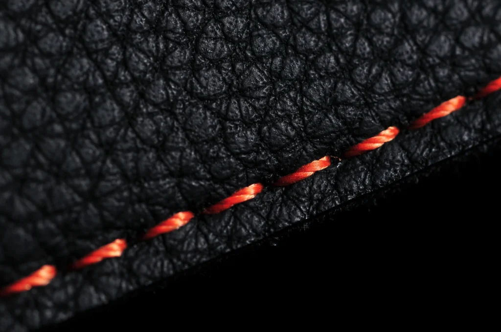 Close-up of black leather with orange contrast stitching
