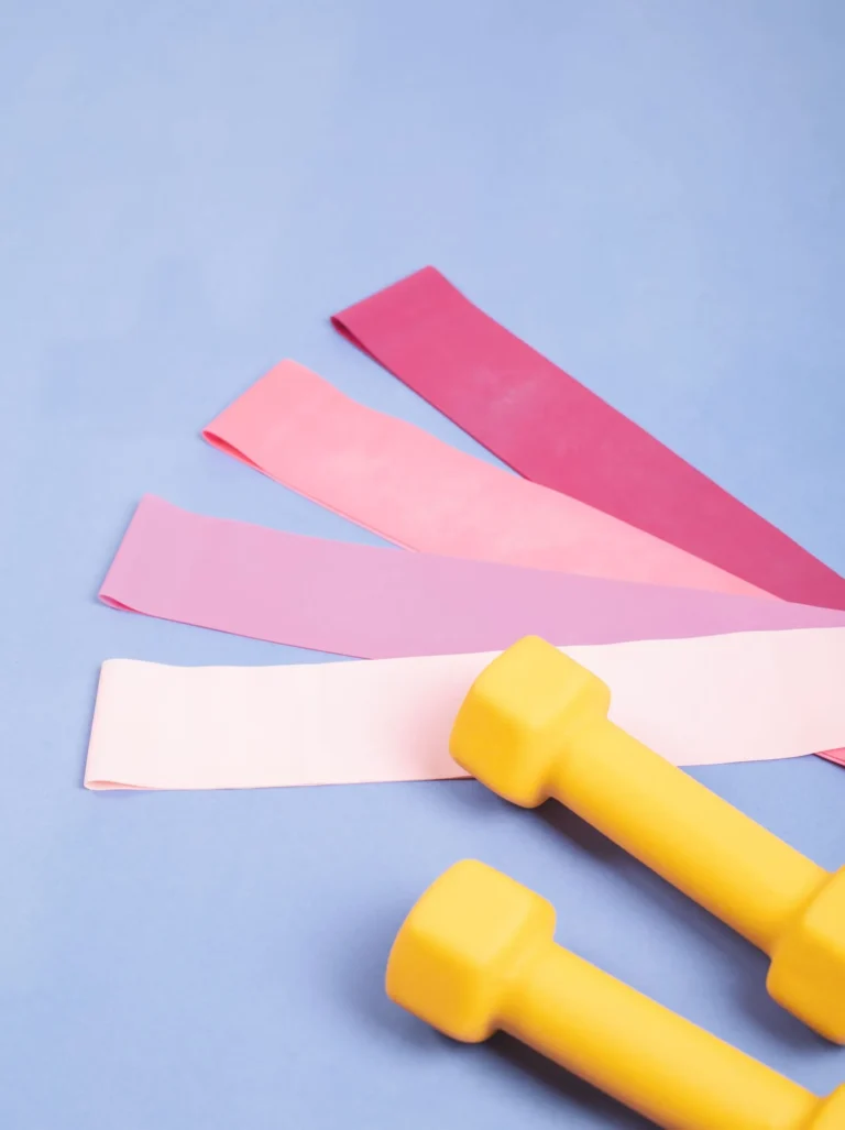 Fabric resistance bands and dumbbells on a pastel background