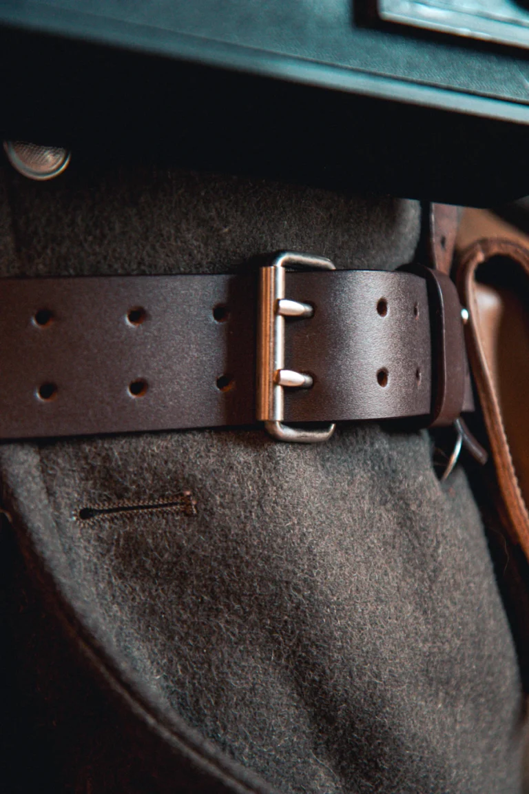 Close-up of a leather weightlifting belt with double-prong steel buckle