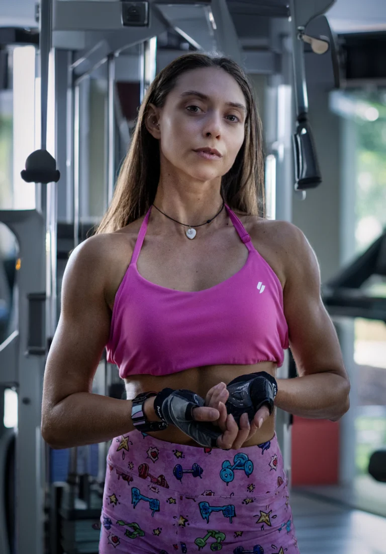 Woman in pink activewear wearing gym gloves in a training gym